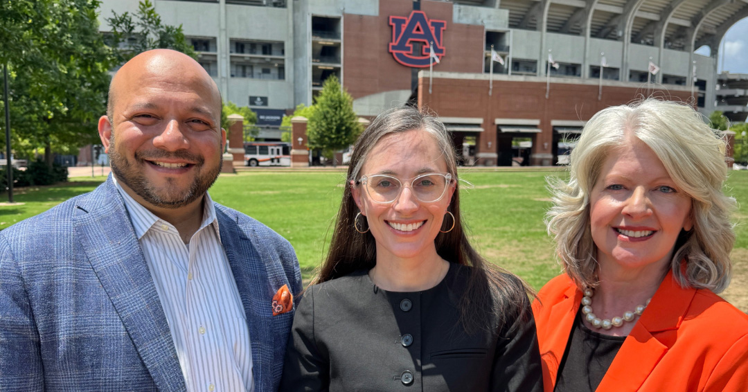 Asim Ali, Moriah Kent, and Jill Albin-Hill in front of AU logo